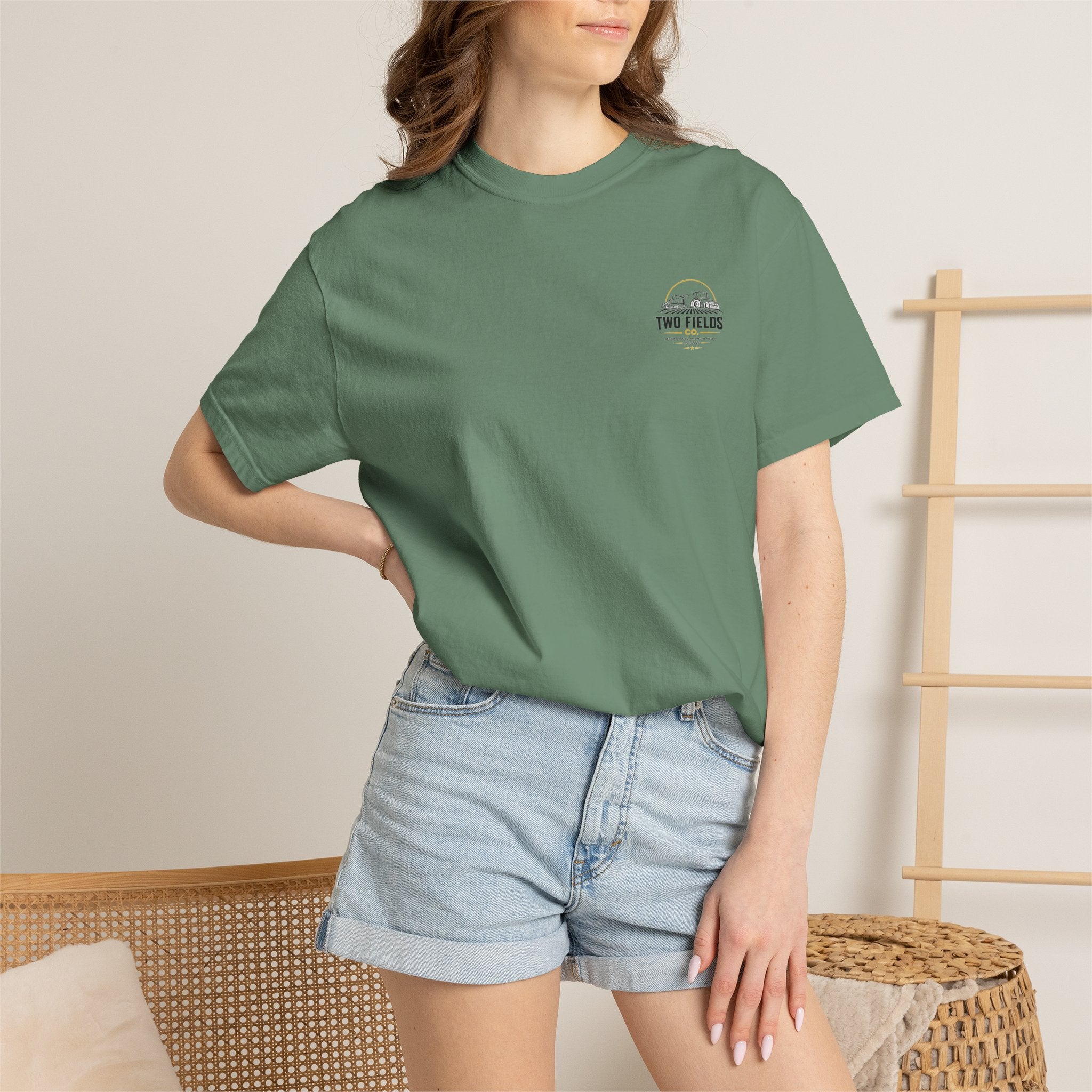 Model wearing olive green t-shirt with small Two Fields Co. logo on chest